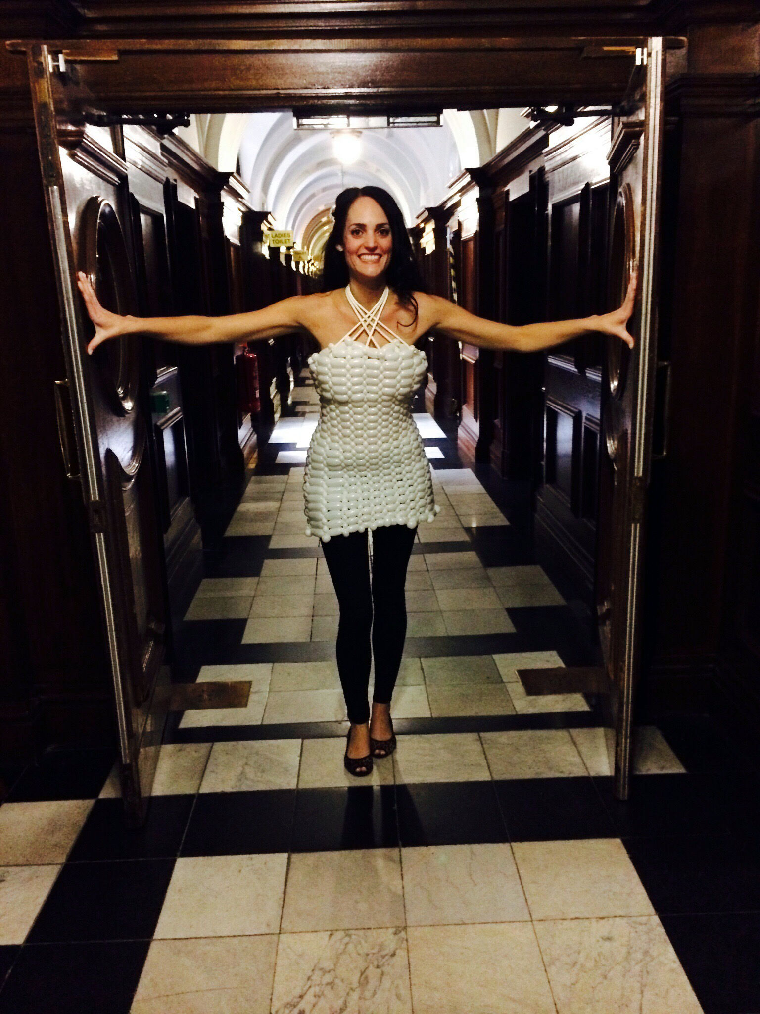 Model wearing a white balloon tunic dress making a grand entrance through a doorway